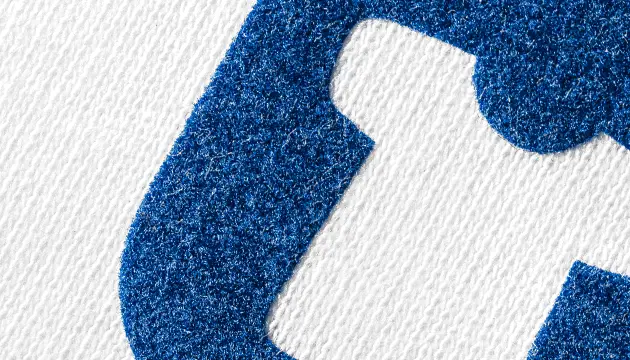 Flockdruck – samtiges Logo auf dunklem Hoodie, taktile Textur sichtbar